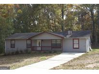 Charming single-story home featuring neutral siding, red window trim, and a cozy front porch at 321 Summerwood Ln, Stockbridge, GA 30281