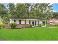 Charming single-story home with a well-manicured lawn, mature trees, and cozy carport at 2566 Nw Santa Barbara Dr, Atlanta, GA 30318