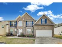 Charming two-story home with brick facade, blue shutters, and well-manicured landscaping at 540 Hamlet Dr, Hampton, GA 30228
