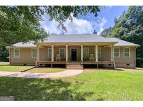 Charming home featuring a welcoming front porch with decorative columns and a well-maintained lawn at 575 Chuli Rd, Locust Grove, GA 30248
