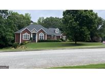 Charming brick home with lush green lawn, mature trees, and manicured landscaping providing excellent curb appeal at 9039 River Bend Ct, Villa Rica, GA 30180