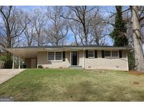 Charming brick home featuring a well-maintained lawn and a convenient carport at 1751 Woodsloe Dr, Decatur, GA 30035
