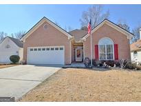 Charming single-story brick home featuring an attached two-car garage and an American flag at 170 Habersham Dr, Fayetteville, GA 30214