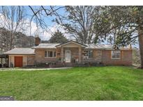 Charming brick home featuring a metal roof, shutters, and a lush green lawn at 100 Cross Plains Hulett Rd, Carrollton, GA 30116