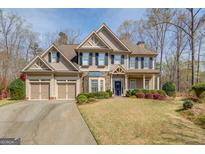 Charming two-story home with a three-car garage, manicured lawn, and a welcoming entrance at 5808 Deer Crossing Dr, Sugar Hill, GA 30518