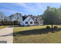Charming white home with a welcoming front porch, green lawn, and a long driveway leading to the house at 1222 Snapping Shoals Rd, Mcdonough, GA 30252
