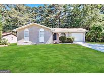 Charming one-story home featuring a brick exterior, well-maintained lawn, and mature trees at 6635 Hidden Brook Trl, South Fulton, GA 30349