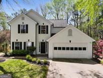 Charming two-story white brick home featuring black shutters, an attached garage, and a well-manicured front lawn at 335 Aqueduct Ct, Alpharetta, GA 30022