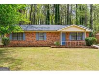 Charming one-story brick home with blue shutters and a well-maintained front lawn and mature trees at 204 Doubletrace Ln, Peachtree City, GA 30269