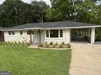 Charming home featuring a covered carport, fresh landscaping, and a welcoming blue front door at 2502 Miriam Ln, Decatur, GA 30032