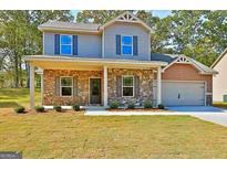 Charming two-story home featuring stone accents, a covered porch, and an attached two-car garage at 648 Stevens Pl, Mcdonough, GA 30252