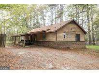 Cozy home exterior featuring a covered porch, classic siding, and brick foundation, nestled in a wooded lot at 6546 Haines Trl, Sharpsburg, GA 30277