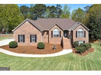 Charming brick home featuring a landscaped front yard, garden beds, and a welcoming entrance staircase at 249 Edenwylde Ct, Hampton, GA 30228