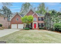 Charming brick home featuring a two-car garage, manicured lawn, and a vibrant red front door at 10460 Cranchester Way, Alpharetta, GA 30022
