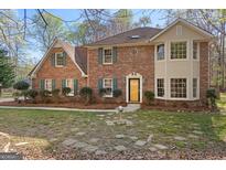 Traditional brick home with a yellow front door, green shutters, and manicured landscaping at 110 Windsor Hts, Fayetteville, GA 30215