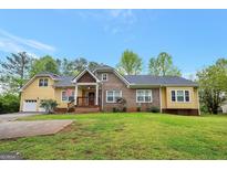 Charming home with brick and yellow siding, featuring a welcoming front porch and well-maintained lawn at 4050 Old Fairburn Rd, Atlanta, GA 30349