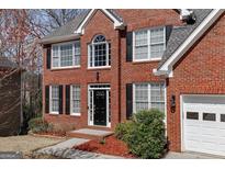 Charming two-story brick home with black shutters, a well-manicured lawn, and attached garage at 2032 Stonewick Ct, Lawrenceville, GA 30043