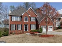 Charming two-story red brick home featuring a two-car garage and well-manicured landscaping at 2032 Stonewick Ct, Lawrenceville, GA 30043