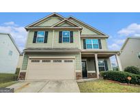Charming two-story home with a two-car garage, stone accents, green siding, and a manicured lawn at 851 Pine Arbor Ln, Lawrenceville, GA 30043