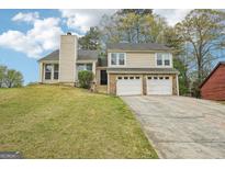 Charming two-story home featuring a two-car garage and a well-maintained front yard with mature trees at 909 Chapman Cir, Stone Mountain, GA 30088