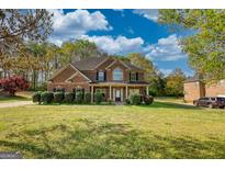 Charming two-story brick home with a well-manicured lawn and lush green landscaping at 117 Berkeley Way, Hampton, GA 30228