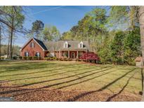 Charming brick home featuring a spacious front yard with mature trees and a welcoming covered porch at 1744 Elks Club Rd, Covington, GA 30014
