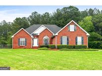 Charming brick home with a well-manicured lawn and mature trees in the background, showcasing classic suburban living at 205 Wynnfield Way, Mcdonough, GA 30252