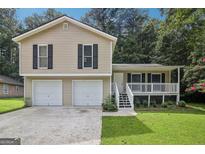 Charming home featuring a two-car garage, front porch, and a well-manicured lawn at 3980 Carlton Cove Ct, Loganville, GA 30052