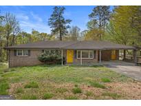 Charming brick ranch-style home with a yellow door, covered porch, and well-maintained landscaping at 6064 Oak Hill Dr, Austell, GA 30168