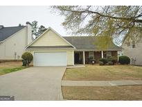 Charming single-Gathering home features a well-maintained lawn and a two-car garage with yellow siding at 2793 Saddle Horn Pl, Snellville, GA 30039
