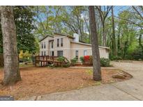 Charming two-story home with a wooden deck, lush landscaping, and a quaint, cozy feel nestled among the trees at 5296 Golfcrest Cir, Stone Mountain, GA 30088