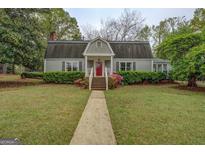 Charming home with a red front door, manicured lawn, and lush landscaping at 6140 Ginn Se St, Covington, GA 30014