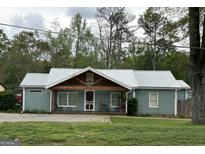 Charming single-story home with a metal roof and inviting front porch with seating at 6121 N Main Se St, Acworth, GA 30101
