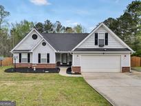 Charming single-story home with a well-manicured lawn, dark roof, and attached two-car garage at 20 Madison Ct, Covington, GA 30016