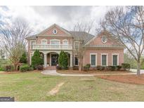 Grand two-story brick home with a covered balcony, columned entryway, and professionally landscaped front yard at 217 Brunswick Dr, Tyrone, GA 30290