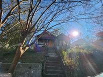 A neglected home exterior with a boarded front door, visible damage, and an overgrown yard needing significant restoration at 950 Joseph E Boone Nw Blvd, Atlanta, GA 30314