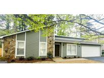 Charming home featuring stone accents, light green siding, a well-maintained lawn, and an attached garage at 1475 Woodington Cir, Lawrenceville, GA 30044