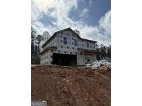 Two story home under construction with visible house wrap, a garage, and lumber strewn about the red clay property at 523 Courthouse Park Dr, Temple, GA 30179