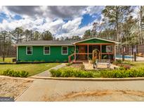 Charming green home featuring a covered porch, landscaped garden, and quaint walkway at 168 Lakeview Dr, Grantville, GA 30220