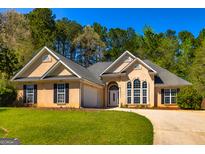 Inviting single-Gathering home with a well-manicured lawn, an attached garage, and a symmetrical facade at 230 Hidden Brook Trl, Fayetteville, GA 30215