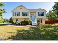 Charming yellow home with a welcoming front porch and manicured lawn and dark shutters at 3540 Owl Brow Ct, Cumming, GA 30028