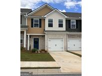 Townhome features brick accents, a two-car garage, and a blue front door at 8708 Lakeview Commons # 47, Jonesboro, GA 30238