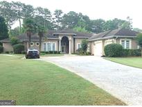 Beautiful home with a well-manicured lawn, circular driveway, and palm trees at 6279 Giles Rd, Lithonia, GA 30058