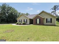 Charming single-story home with green lawn, brick facade, black shutters and manicured landscaping at 321 Harris Ave, Locust Grove, GA 30248
