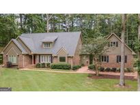 Charming single-Gathering home with brick accents, lush landscaping, and a well-manicured lawn surrounded by mature trees at 107 Rolling Grn, Peachtree City, GA 30269