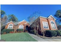 Stately brick home featuring a manicured front lawn, mature landscaping and arched windows at 1090 Crown River Pkwy, Mcdonough, GA 30252