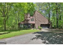 Contemporary home featuring a unique angled roofline, attached garage, and nestled among lush greenery at 2451 Cedar Fork Trl, Marietta, GA 30062