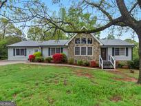 Charming home with stone accents, gray siding, beautiful landscaping and mature trees in front yard at 121 Cotton Indian Trl, Stockbridge, GA 30281