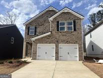 Two-story brick home with a two-car garage and a well-manicured lawn under a blue sky at 5318 Tolar Rd # 25, South Fulton, GA 30213