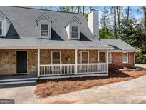 Charming home with a stone facade, dormer windows, and a welcoming front porch at 9055 Carroll Manor Dr, Sandy Springs, GA 30350
